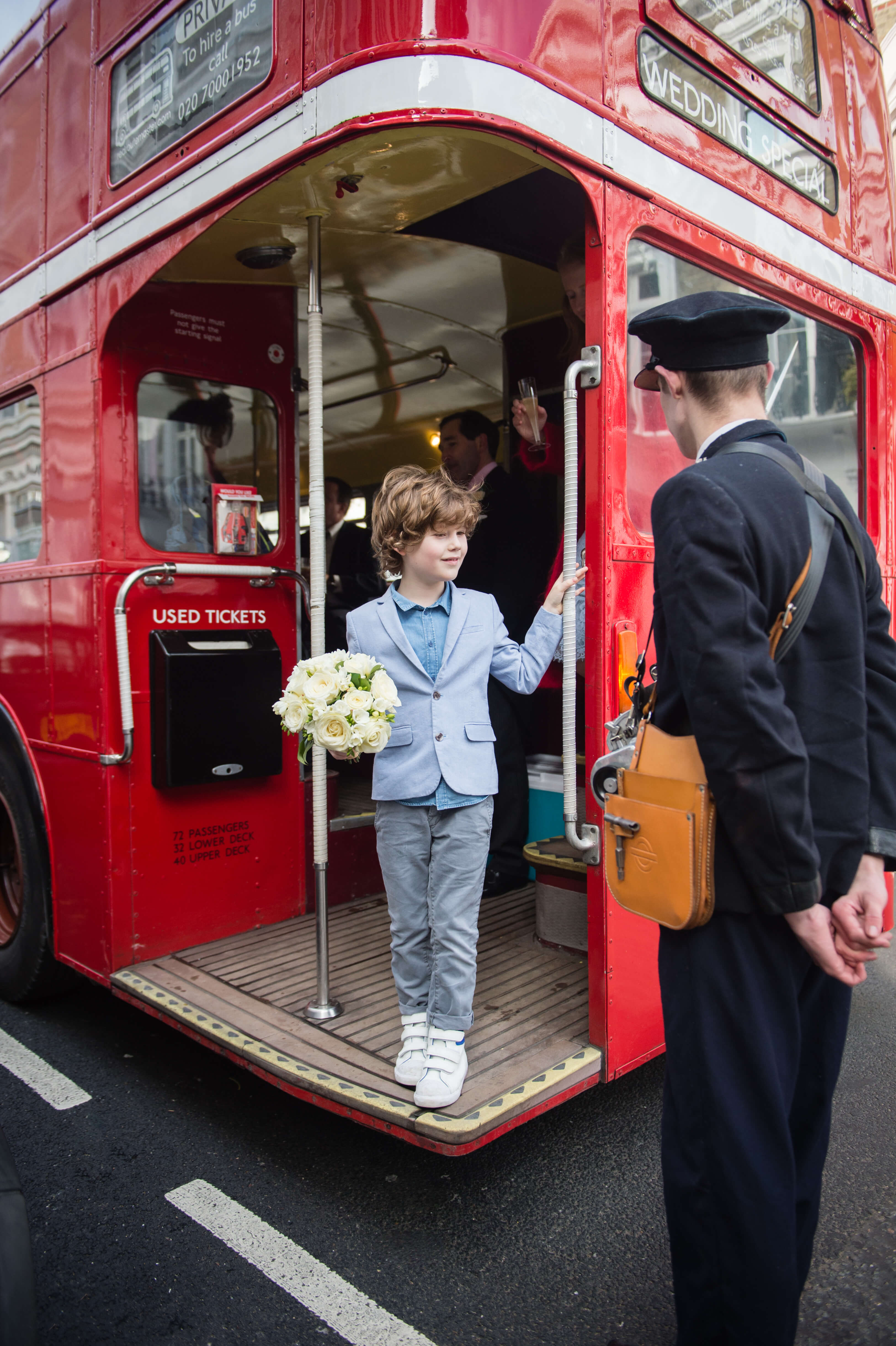 page boy with bouquet on a routemaster wedding bus in chelsea